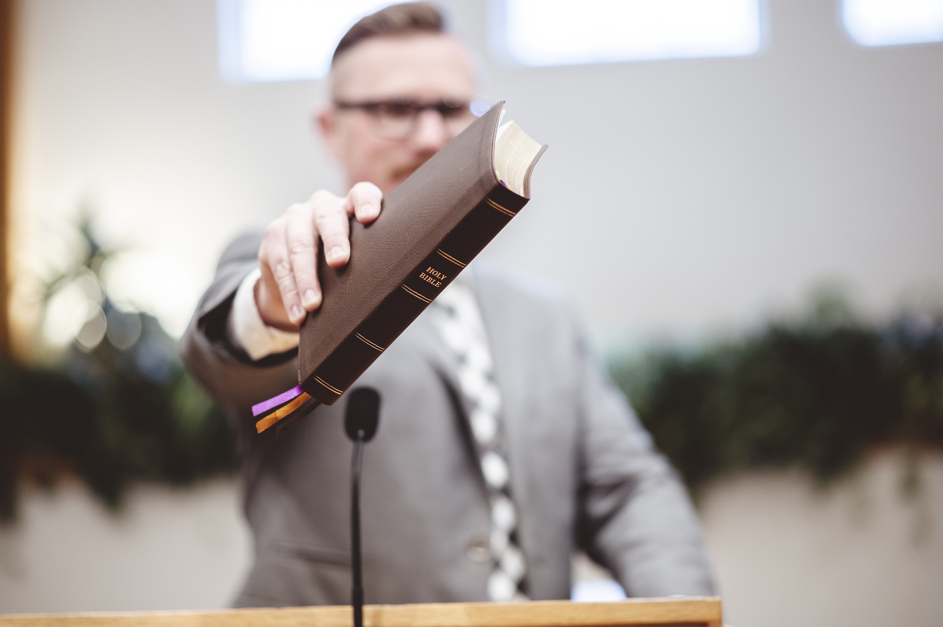 A selective focus shot of a male standing and holding a book in hands